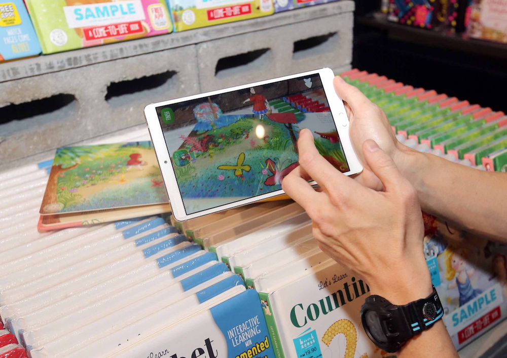 BookXcess founder and managing director Andrew Yap explaining how the Augmented Reality (AR) books work. — Picture by Farhan Najib